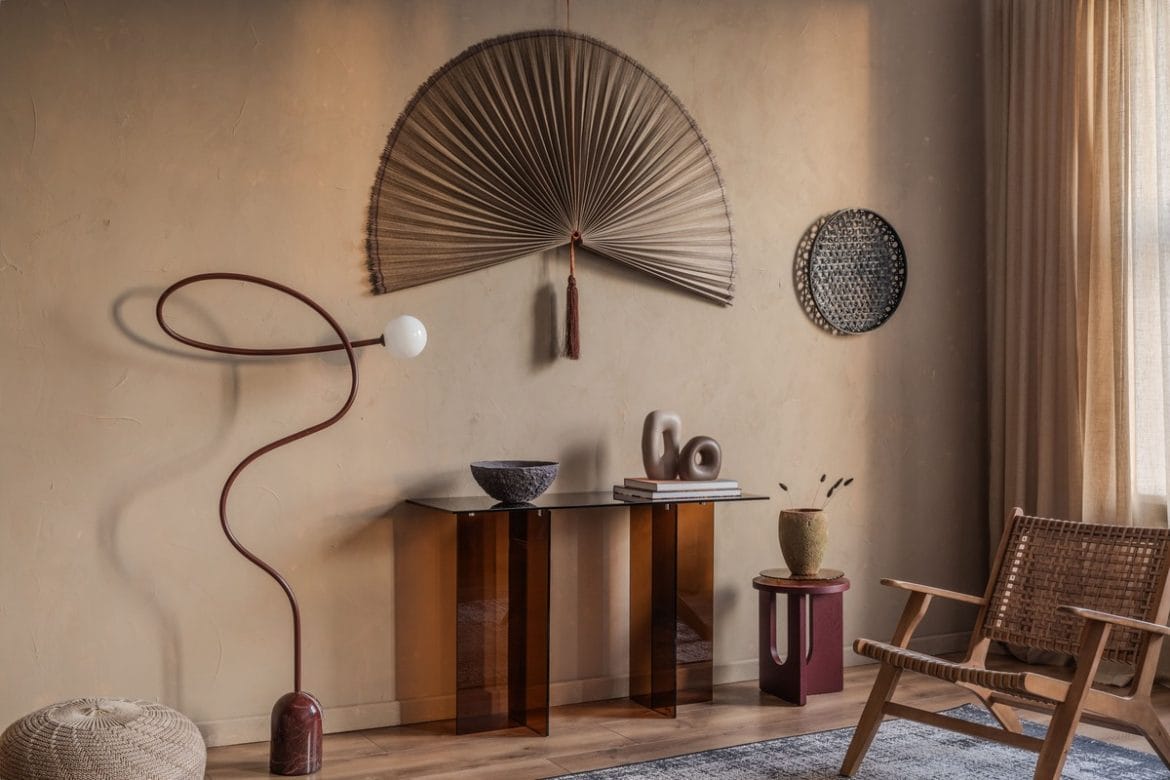 Šviesaus tono svetainė su meno akcentais – sienų dekoru, skulptūromis ir nestandartiniu šviestuvu minimalistiniame interjere.