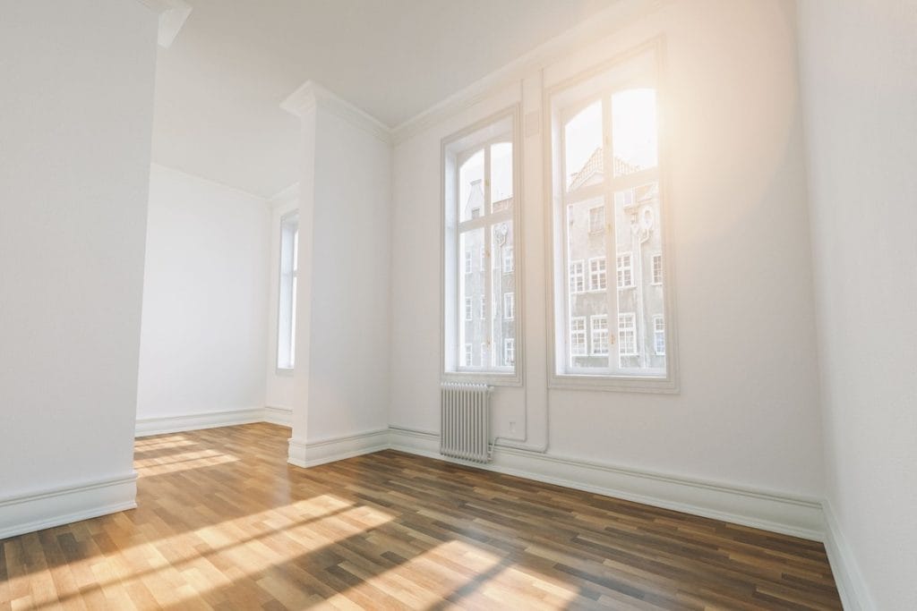 Šviesus kambarys su dideliais langais, natūralia dienos šviesa ir medinėmis grindimis – natūralaus interjero pagrindas.