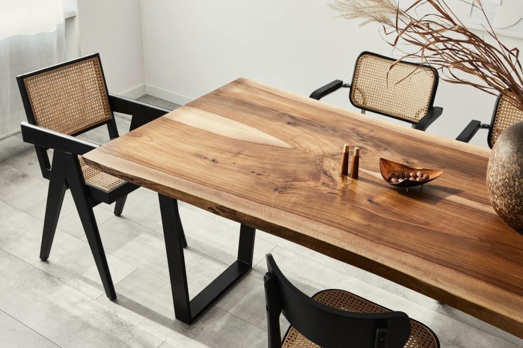 Valgomojo zona su natūralaus medžio stalu ir pintomis kėdėmis – elegantiškas natūralaus interjero sprendimas.