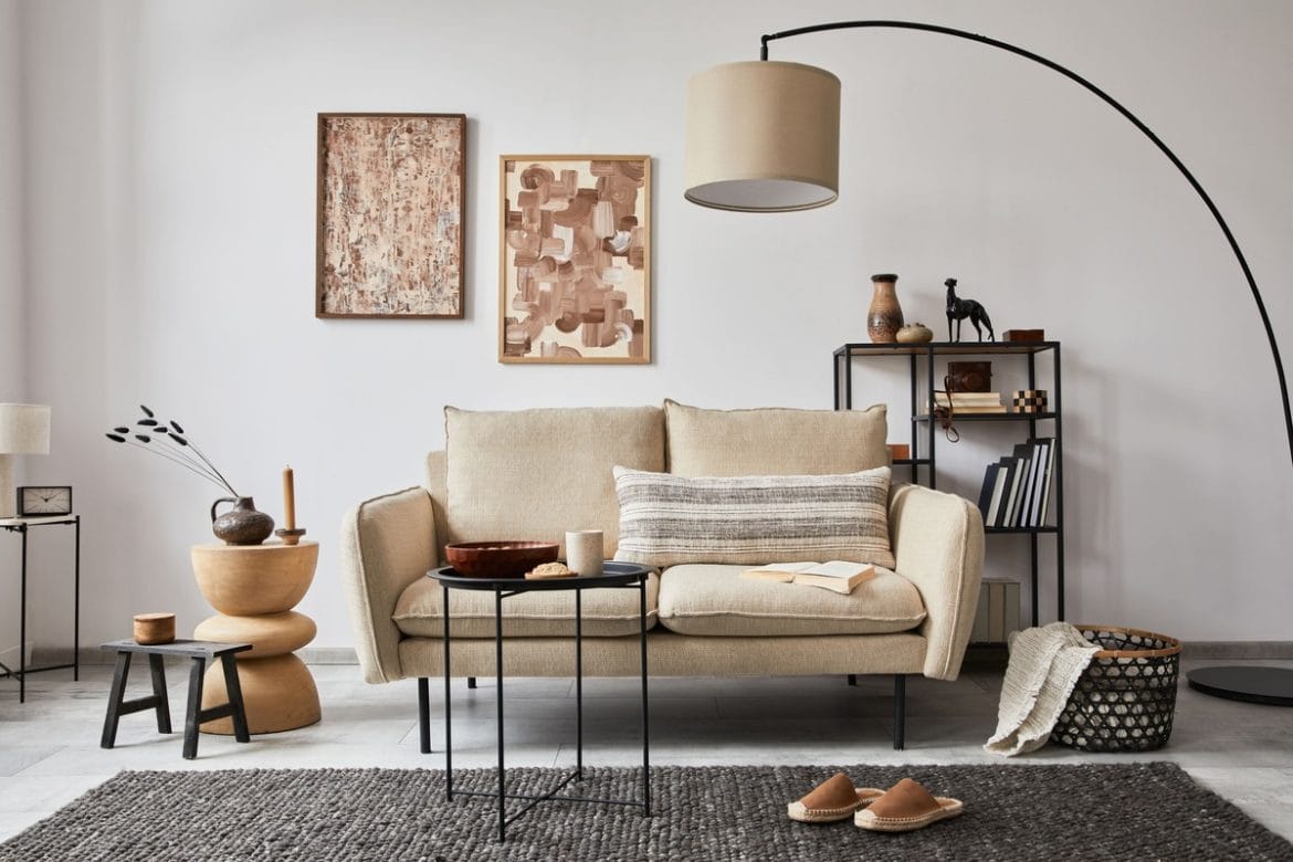 Šviesi, natūralių tonų svetainė su minkšta sofa, neutraliomis sienomis ir lengvais akcentais, kurie optiškai didina erdvę.