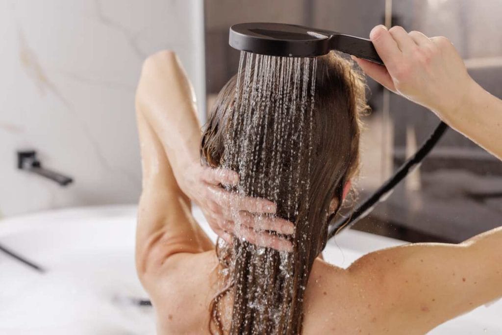 Moteris plauna dažytus plaukus po dušu, kai bėgantis karštas vanduo gali greičiau išplauti pigmentą.