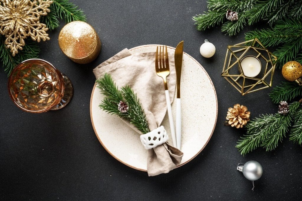 Minimalistinis kalėdinio stalo serviravimas su natūraliomis detalėmis ir eglės šakele