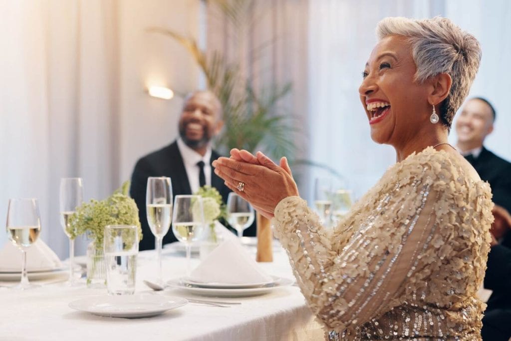 Nuotakos mama vestuvėse su elegantiška suknele ir šilta šypsena.