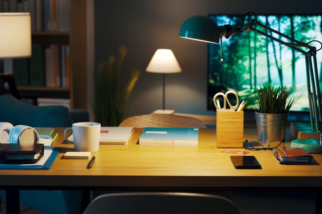 Stilingas namų biuras su tvarkingu darbo stalu, stalo lempa ir minimalistiniu interjeru